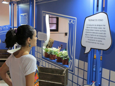 Visitante visualiza cartaz dentro da exposição Dengue